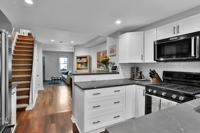 123 Willow Ter, Hoboken, NJ 07030 - kitchen with black range with gas cooktop, a peninsula, tasteful backsplash, wood finished floors, and white cabinets
