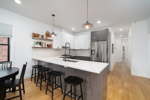 109 Poplar St Unit 1, Jersey City, NJ 07307 - kitchen with stainless steel fridge with ice dispenser, a peninsula, a kitchen bar, light countertops, and recessed lighting