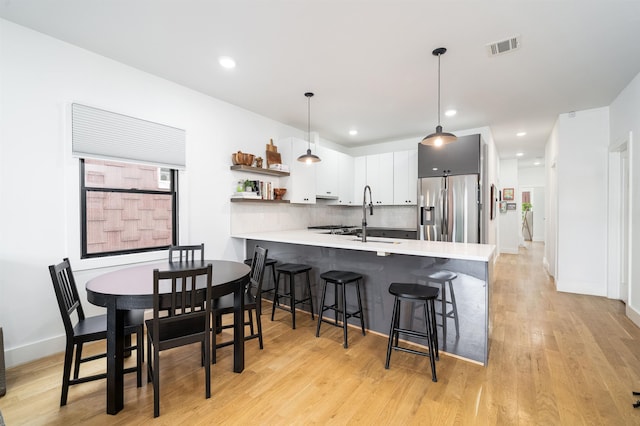 109 Poplar St Unit 1, Jersey City, NJ 07307 - kitchen with stainless steel fridge with ice dispenser, a peninsula, light countertops, a breakfast bar area, and backsplash