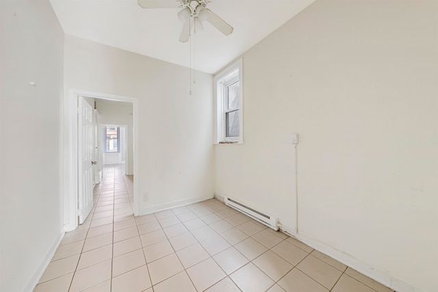 empty room featuring light tile patterned flooring, ceiling fan, and a baseboard radiator