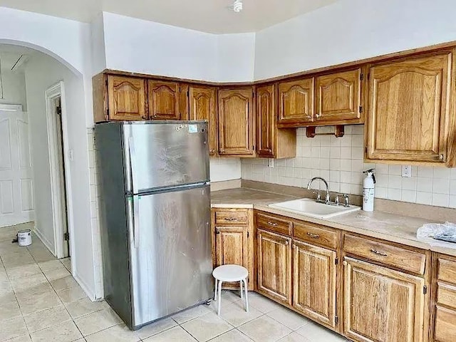 kitchen featuring light tile patterned flooring, sink, stainless steel fridge, and backsplash