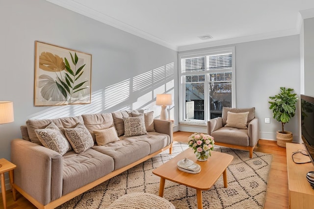 living area with visible vents, crown molding, and light wood-style flooring