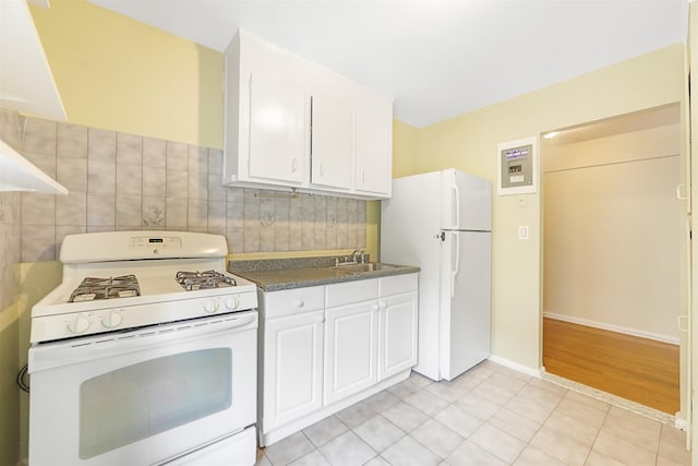 kitchen with white appliances, white cabinetry, a sink, dark countertops, and tasteful backsplash