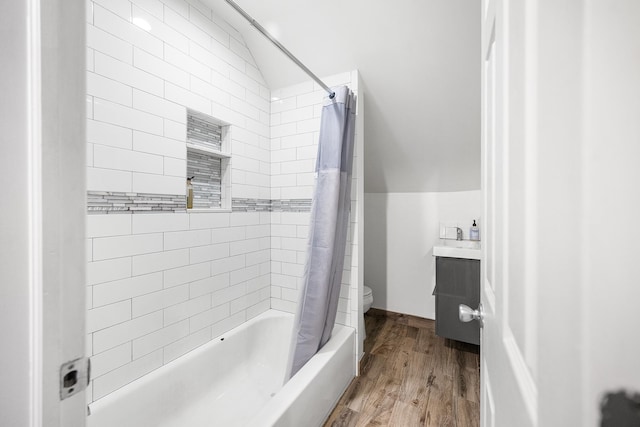 bathroom featuring toilet, wood finished floors, shower / tub combo with curtain, vaulted ceiling, and vanity