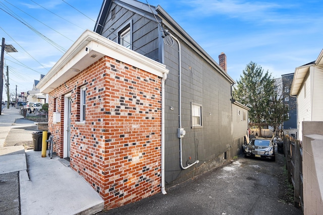 view of side of property featuring brick siding and fence