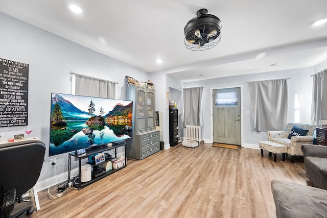 living room featuring radiator, wood finished floors, and recessed lighting