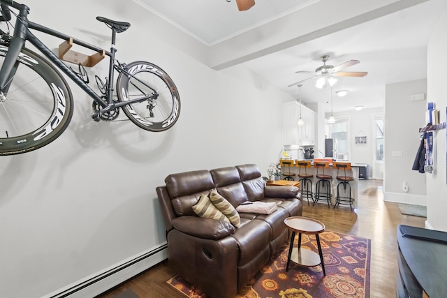 living room featuring baseboard heating, dark hardwood / wood-style flooring, ornamental molding, and ceiling fan