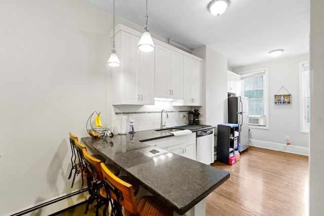 kitchen featuring kitchen peninsula, a kitchen bar, decorative light fixtures, and white cabinetry