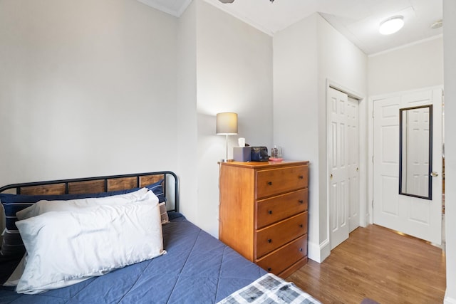 bedroom with a closet, crown molding, and hardwood / wood-style flooring