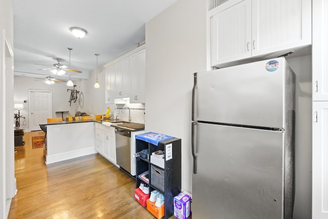 kitchen featuring decorative light fixtures, white cabinetry, appliances with stainless steel finishes, and kitchen peninsula