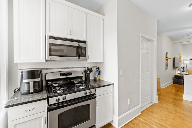 kitchen featuring ceiling fan, white cabinetry, stainless steel appliances, and light wood-type flooring