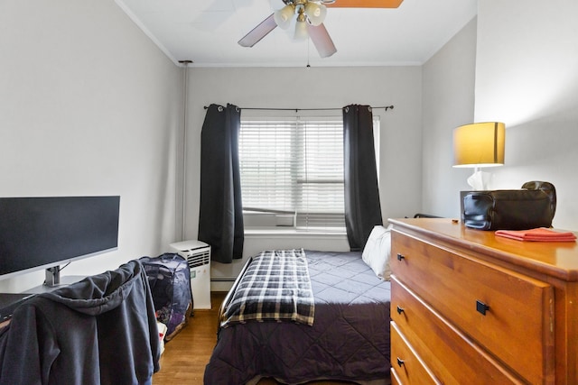 bedroom featuring ceiling fan, light wood-type flooring, baseboard heating, and crown molding