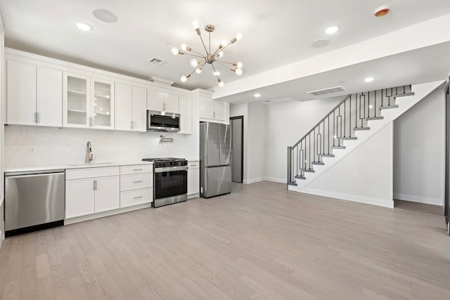 kitchen featuring white cabinetry, sink, stainless steel appliances, tasteful backsplash, and light hardwood / wood-style floors