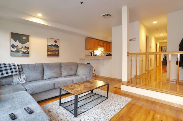 living area with recessed lighting, visible vents, light wood-style flooring, and baseboards