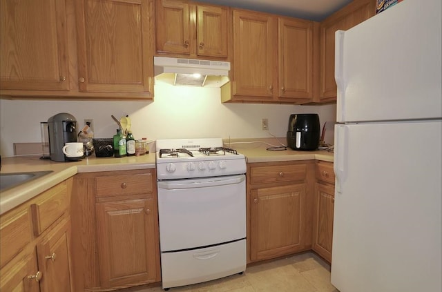 kitchen with white appliances, light countertops, and under cabinet range hood