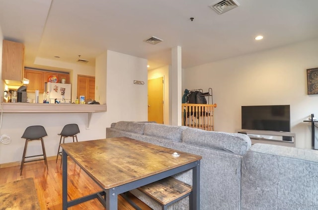 living area with recessed lighting, wood finished floors, visible vents, and baseboards