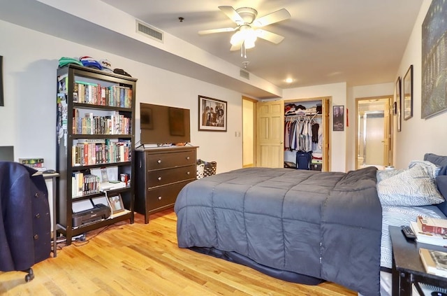 bedroom featuring a closet, visible vents, ensuite bath, and wood finished floors