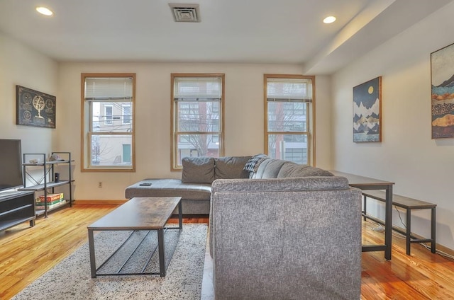 living area featuring a wealth of natural light, visible vents, and wood finished floors