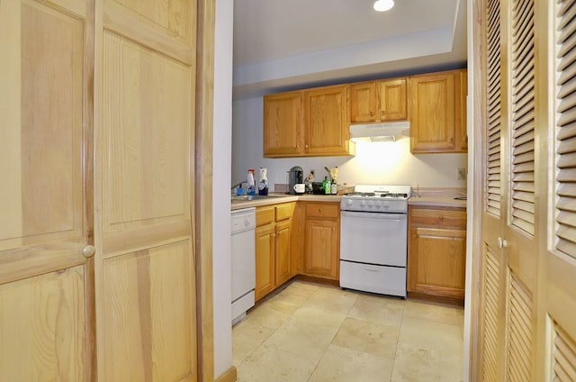 kitchen featuring under cabinet range hood, white appliances, and light countertops