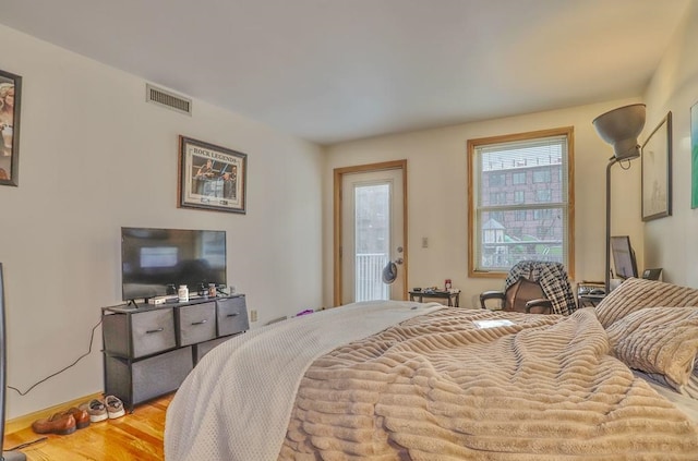 bedroom with access to exterior, wood finished floors, visible vents, and baseboards