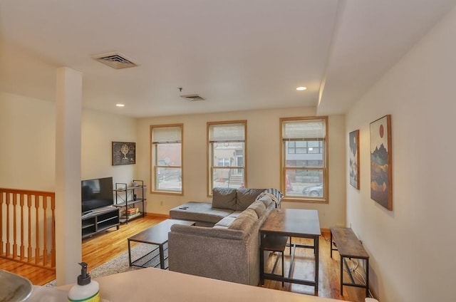 living area featuring visible vents, a healthy amount of sunlight, and wood finished floors