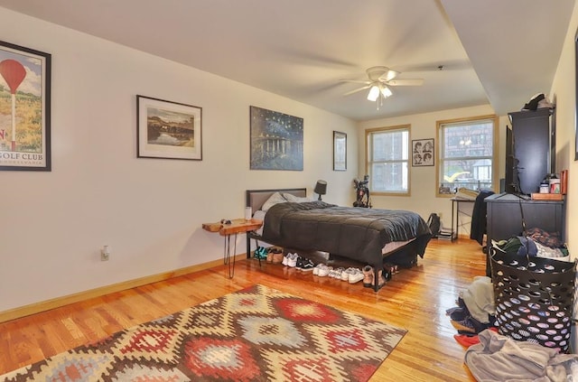 bedroom featuring baseboards, wood finished floors, and a ceiling fan