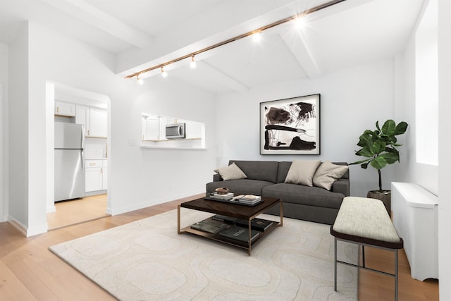 living room with track lighting, baseboards, beam ceiling, and light wood-style flooring