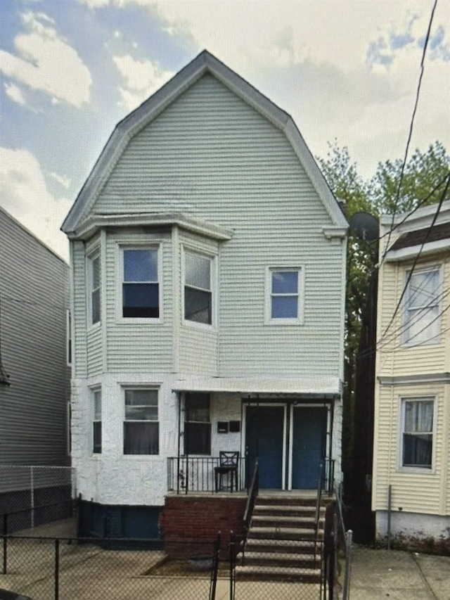 217 Bidwell Ave, Jersey City, NJ 07305 - dutch colonial featuring covered porch, a fenced front yard, and a gambrel roof