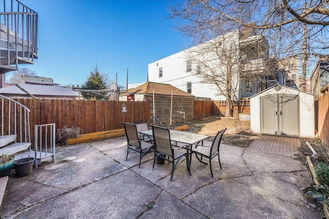 view of patio featuring an outbuilding, a shed, outdoor dining area, and a fenced backyard