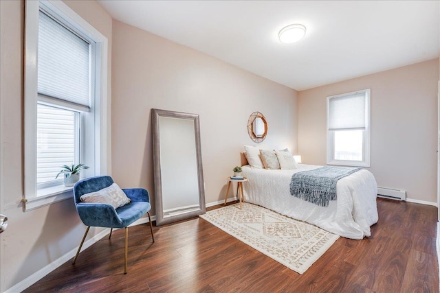 bedroom featuring a baseboard heating unit, wood finished floors, and baseboards