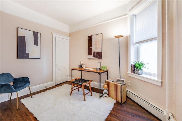 living area featuring a baseboard heating unit, baseboards, and dark wood-style flooring