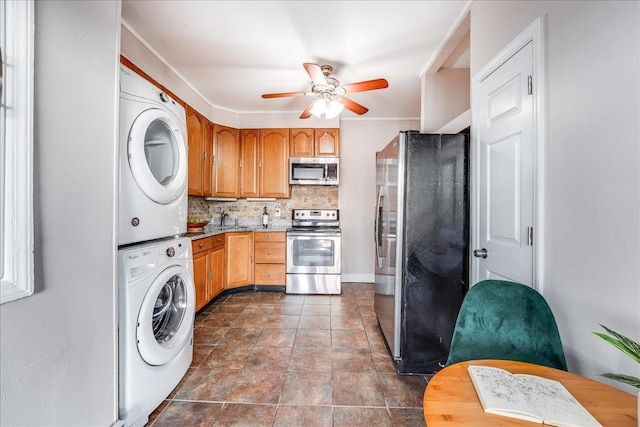 kitchen with ceiling fan, decorative backsplash, a sink, stainless steel appliances, and stacked washer and clothes dryer