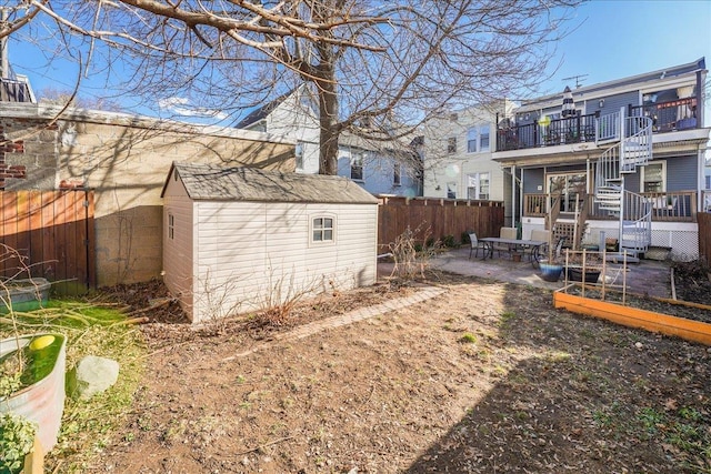 view of yard featuring a patio, a garden, a fenced backyard, an outdoor structure, and a storage unit