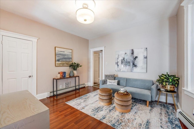 sitting room with a baseboard heating unit, baseboards, and wood finished floors