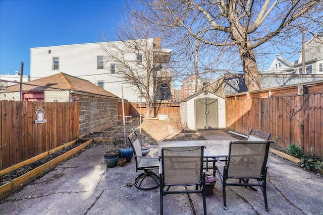 view of patio featuring outdoor dining space, a storage shed, an outbuilding, and a fenced backyard