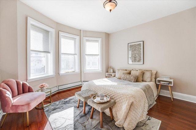 bedroom featuring baseboard heating, multiple windows, baseboards, and wood finished floors