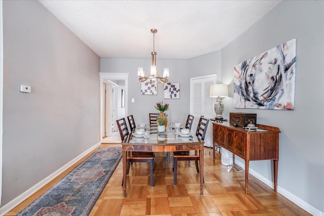 dining area with a notable chandelier, baseboards, and a textured ceiling