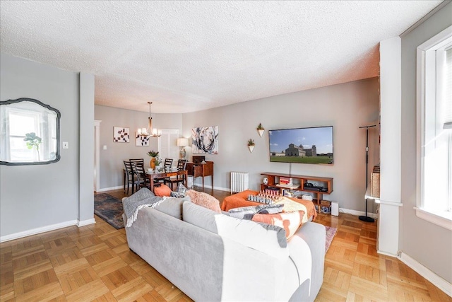 living area with a notable chandelier, radiator heating unit, baseboards, and a textured ceiling