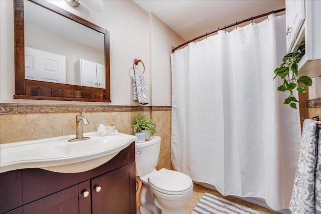 bathroom featuring toilet, tile walls, wainscoting, tile patterned flooring, and vanity