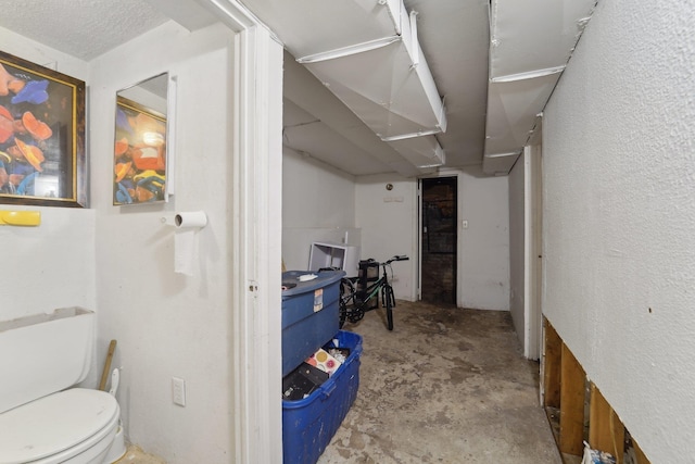 interior space with a textured ceiling, toilet, and concrete flooring