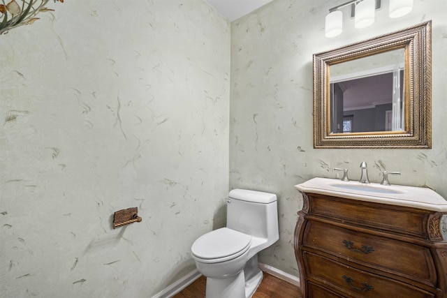 bathroom featuring toilet, vanity, baseboards, and wood finished floors