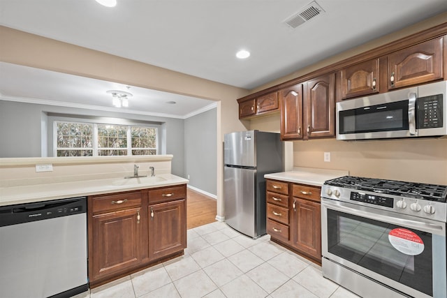 kitchen with visible vents, ornamental molding, a sink, appliances with stainless steel finishes, and light countertops