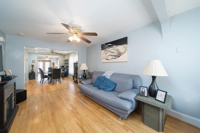 living area with a ceiling fan, light wood-style flooring, and baseboards