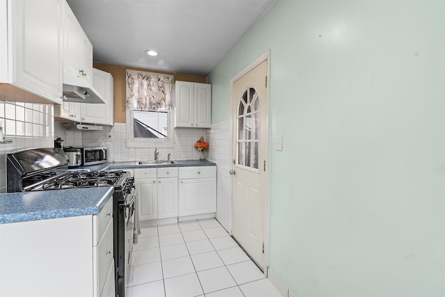 kitchen featuring white cabinets, range with gas stovetop, stainless steel microwave, a sink, and light tile patterned flooring