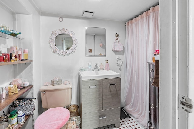 bathroom featuring toilet, vanity, and visible vents