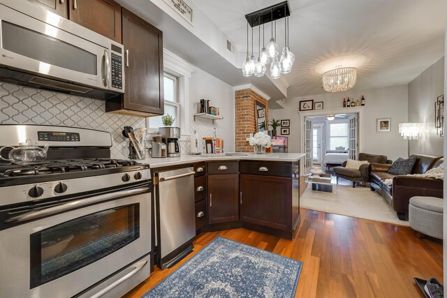 380 7th St Unit 2A, Jersey City, NJ 07302 - kitchen featuring appliances with stainless steel finishes, open floor plan, dark brown cabinetry, a chandelier, and backsplash
