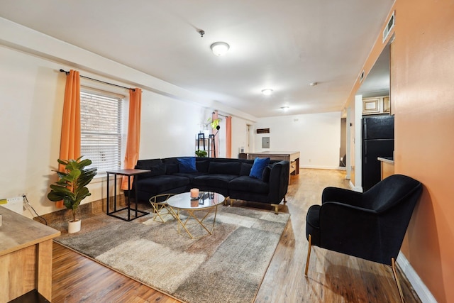 living room with wood finished floors, visible vents, and baseboards