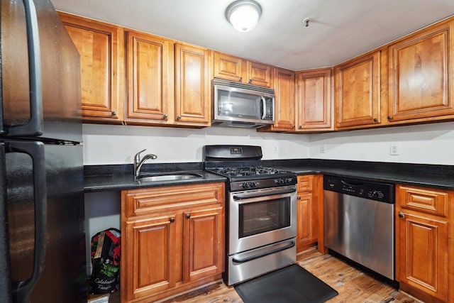 kitchen with appliances with stainless steel finishes, brown cabinets, and a sink