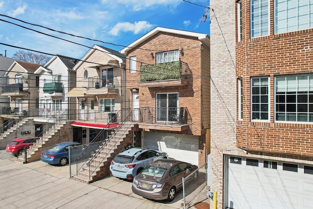 view of front of property with a garage, brick siding, driveway, and stairway