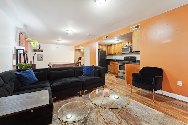 living room featuring light wood-style floors, visible vents, and baseboards